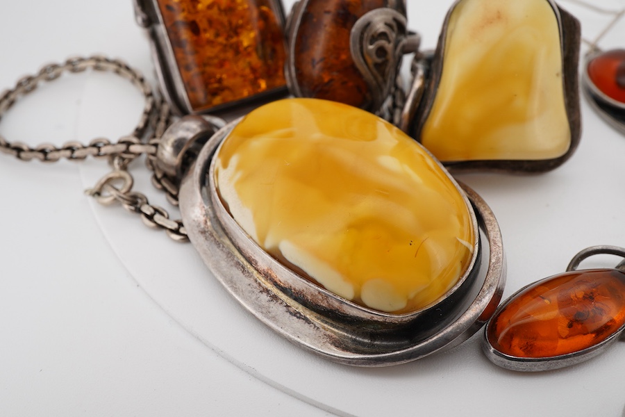 A collection of silver and amber jewels, comprising: two pairs of pendent earrings, three rings and a pendant necklace, all set with amber, mounted in silver; together with a silver and tiger's eye pendant necklace